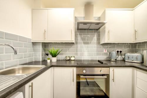 a kitchen with white cabinets and a sink at Two Bed Stylish Apartment in Heart of West End in Glasgow