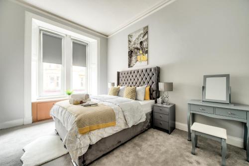 a bedroom with a bed and a desk with a mirror at Two Bed Stylish Apartment in Heart of West End in Glasgow
