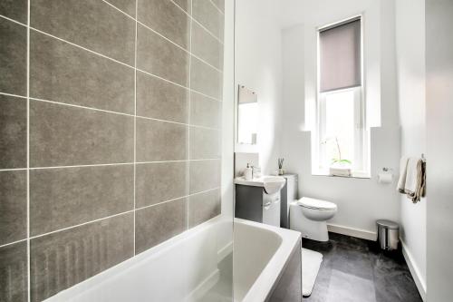 a bathroom with a tub and a toilet and a sink at Two Bed Stylish Apartment in Heart of West End in Glasgow