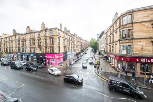 a busy city street with parked cars and buildings at Two Bed Stylish Apartment in Heart of West End in Glasgow