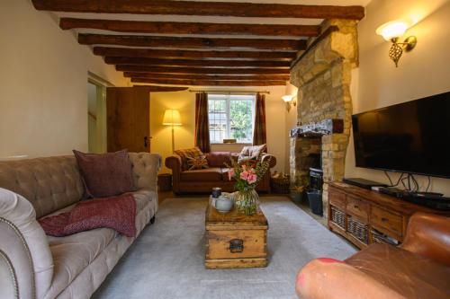 a living room with a couch and a television at The Farthings Cotswolds Holiday Cottage in Chipping Campden