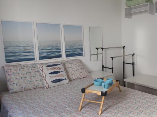 um quarto com uma cama e uma mesa em frente às janelas em Solar Canto do Forte na Praia Grande