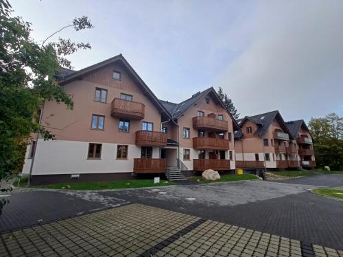 een appartementencomplex met balkons en een parkeerplaats bij Szum Łomnicy in Karpacz