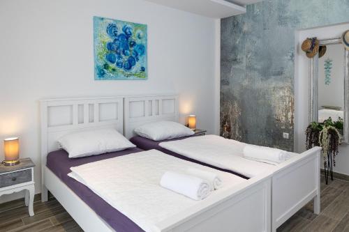two beds in a white bedroom with a painting on the wall at Vila Lavanda in Bribir