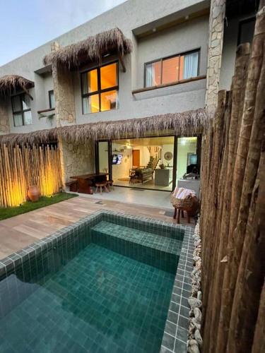 a house with a swimming pool in front of a house at Villa Jucá Casa 03 in Pôrto de Pedras