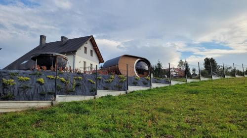 una casa su una collina con una recinzione e girasoli di Górskie Przysiółki w Koniakowie - Dom z Widokiem Szańce a Koniaków
