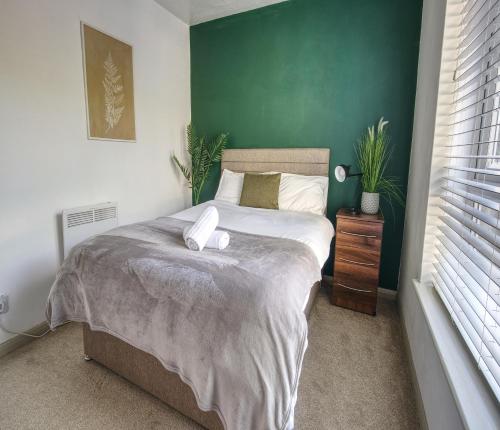 um quarto com uma cama com uma parede verde em #1 Limes by DerBnB, Modern 1 Bedroom Apartment, Free Parking, WI-FI & Netflix Near Royal Derby Hospital em Derby