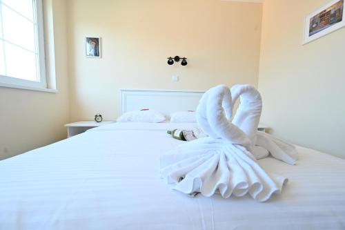 ein weißes Bett mit zwei Schwänen aus Handtüchern in der Unterkunft Smeštaj TEA in Vrnjačka Banja