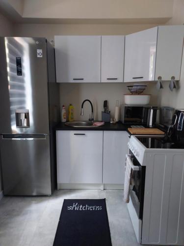 eine Küche mit weißen Schränken und einem Kühlschrank aus Edelstahl in der Unterkunft Apartament Centrum 2 in Wałbrzych
