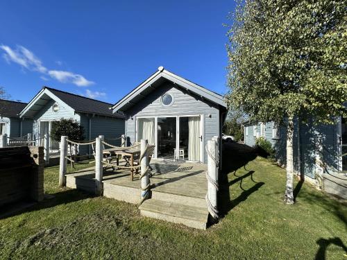 a house with a wooden porch and a fence at Sea-Renity - Part of the The Bay Filey Holiday Village with pool, gym and direct beach access, pub, restaurant, tennis and meadows walks in Filey