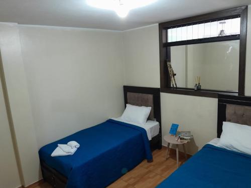 a room with two beds with blue sheets and a window at HOME BLESSED II in Lima