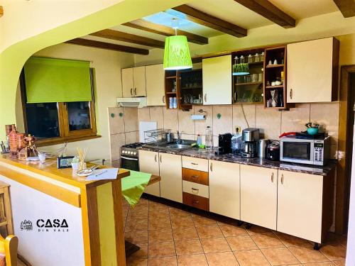 uma cozinha com armários brancos e um tecto verde em Casa din Vale em Moieciu de Sus
