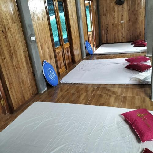 three beds in a room with wooden walls and wooden floors at Homestay and Hots Spring Huy Hường in Yên Bái