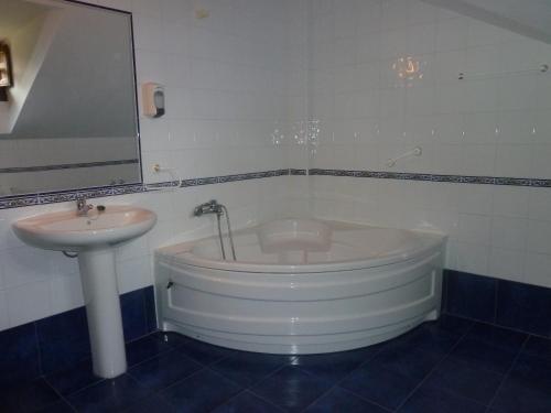 a bathroom with a bath tub and a sink at Hotel Apartamentos La Hortona in Soto de Luiña