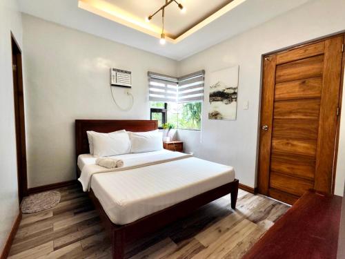 a bedroom with a bed and a wooden door at Bella Homes 6BR near Rotunda, WiFi, Parking in Tagaytay