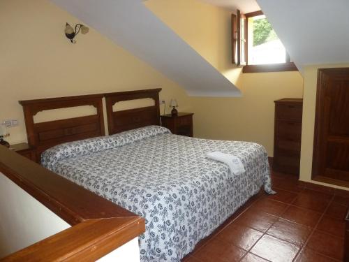 a bedroom with a bed and a staircase with a window at Hotel Apartamentos La Hortona in Soto de Luiña