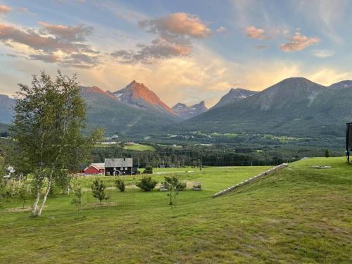 un champ avec une grange et des montagnes en arrière-plan dans l'établissement Villa i Isfjorden!, à Isfjorden