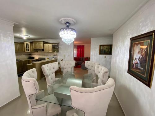 a dining room with a glass table and white chairs at Dominican Rep Nice Apt-2Inverter and Transformer for the power if goes off- 2Good transportation-Comercial area in La Estrella