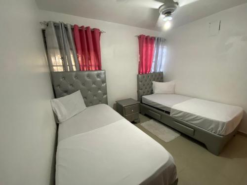 two beds in a small room with red curtains at Dominican Rep Nice Apt-2Inverter and Transformer for the power if goes off- 2Good transportation-Comercial area in La Estrella