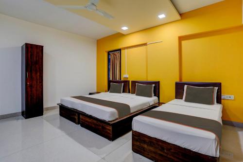 two beds in a room with yellow walls at Collection O Rio Corporate House in Mumbai