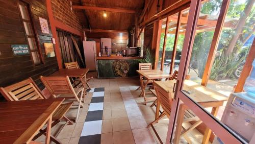 a restaurant with wooden tables and chairs and a kitchen at Hostel Haus in Puerto Iguazú