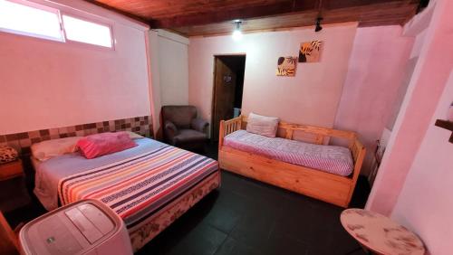 a small bedroom with two beds and a chair at Hostel Haus in Puerto Iguazú