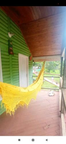 a yellow hammock hanging from a green house at Cabaña del lago in Ciudad del Este