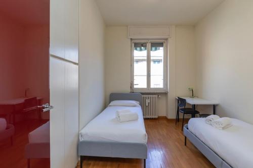 Habitación con 2 camas, mesa y ventana en [IHost Apartment] - Niccolini 21, en Milán