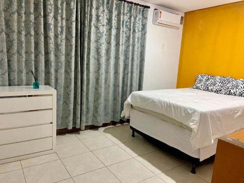 a bedroom with a bed and a dresser and a window at Casa bela in Lauro de Freitas