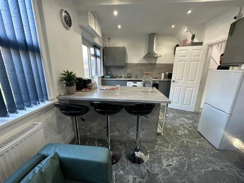 a kitchen with a counter with stools and a refrigerator at Tarleton house in Stoke on Trent
