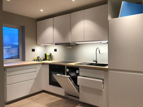 une cuisine avec des armoires blanches et un évier dans l'établissement Fin leilighet i Tromsø, à Tromsø