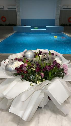 a bouquet of flowers on a table next to a swimming pool at غرف قاعة وشاليه ومسبح ماز in Al Rass