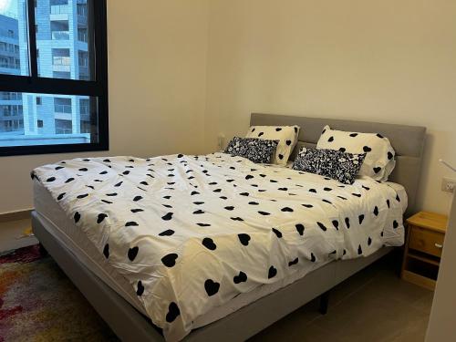 a bed with a white comforter and pillows in a bedroom at New apt Stunning view steps from hospital! in Ramat Gan