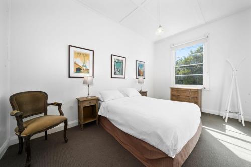 a bedroom with a bed and a chair and a window at Kits Coty in Katoomba