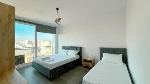 a bedroom with two beds and a large window at Urban Serenity Skyline View Apartment 2 in Tirana