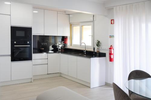 a white kitchen with white cabinets and a window at Sunset House over the Sea in Sesimbra
