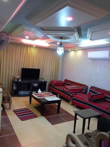 een woonkamer met rode banken en een tv bij شقة مفروشة مكيفة للايجار بجبل طارق 