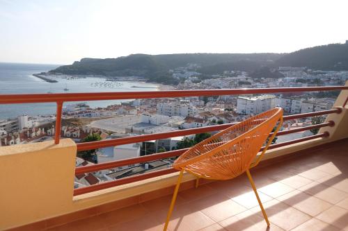 a chair on a balcony with a view of the ocean at Sunset House over the Sea in Sesimbra