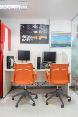 an office with two orange chairs and two monitors at Scout Madrid Hostel in Madrid