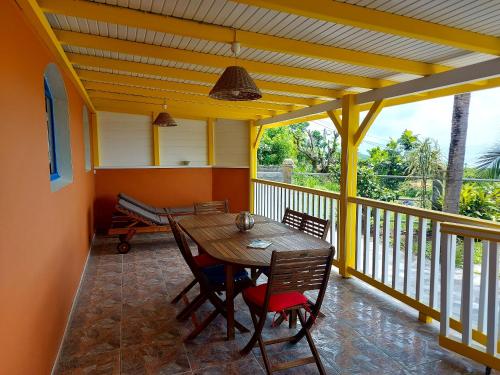 a dining room with a table and chairs on a balcony at Maison charmante à Le Diamant avec vue sur mer et jardin in Le Diamant