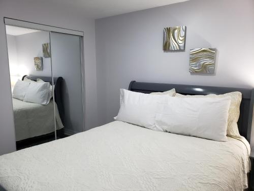 Luxurious 1BR-1BA Apartment Bright Spacious with free parking في برامبتون: غرفة نوم بسرير ومخدات بيضاء ومرآة