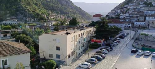 ein großes weißes Gebäude mit Autos auf einem Parkplatz in der Unterkunft RINA'S Apartment in Berat