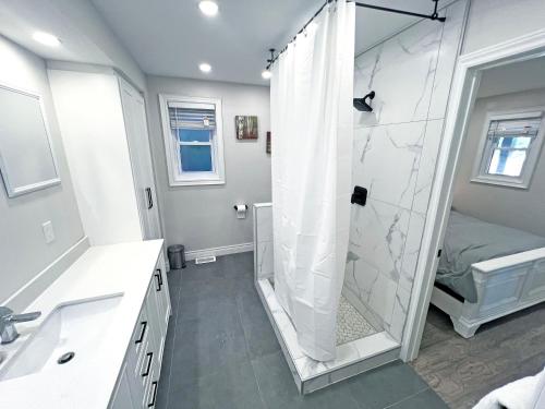 a white bathroom with a shower and a sink at Luxe Home Near Limeridge - Sleeps 11 - Pool in Hamilton