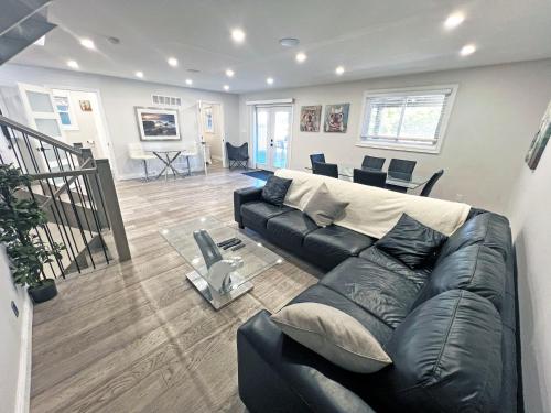 a living room with a black leather couch and a table at Luxe Home Near Limeridge - Sleeps 11 - Pool in Hamilton