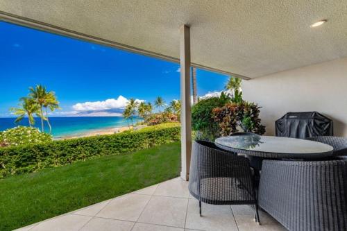 a patio with a table and chairs and the ocean at MAKENA SURF, #C-103 condo in Wailea