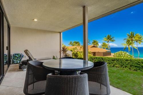 a table and chairs on a patio with a view of the ocean at MAKENA SURF, #C-103 condo in Wailea