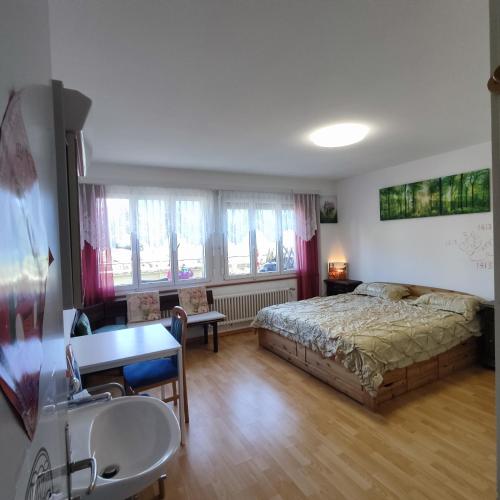 a bedroom with a bed and a desk and windows at THE BEST LAKE HOUSE -3 minutes to the train in Spiez