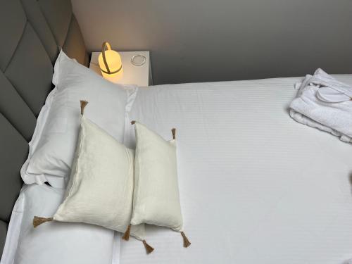 a white bed with white pillows and a lamp at Fonte Retreat Premium Suite in Sandim