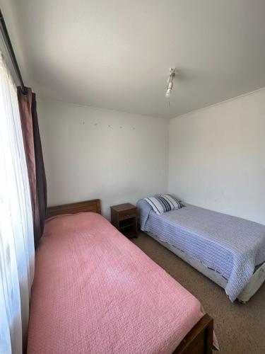 a bedroom with two beds and a pink blanket at Habitación casa condominio in Coquimbo