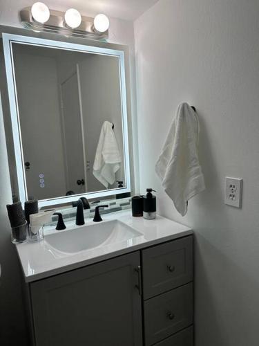 a bathroom with a sink and a large mirror at Backyard Oasis in Port Saint Lucie